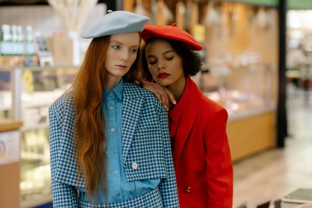Deux femmes portant des looks vintage colorés avec bérets français, blazer à carreaux vichy bleu et tailleur rouge rétro années 80